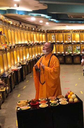 A Buddhist monk conducting An Ling prayers before memorial tablets and offerings
