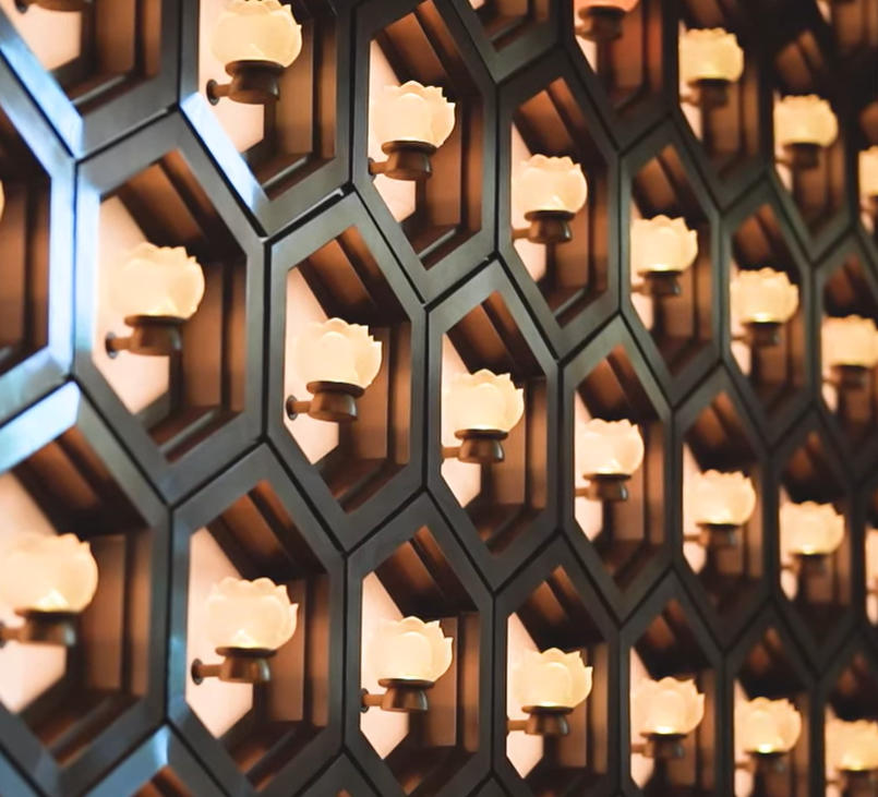 Warm lotus-shaped lights lining a memorial wall